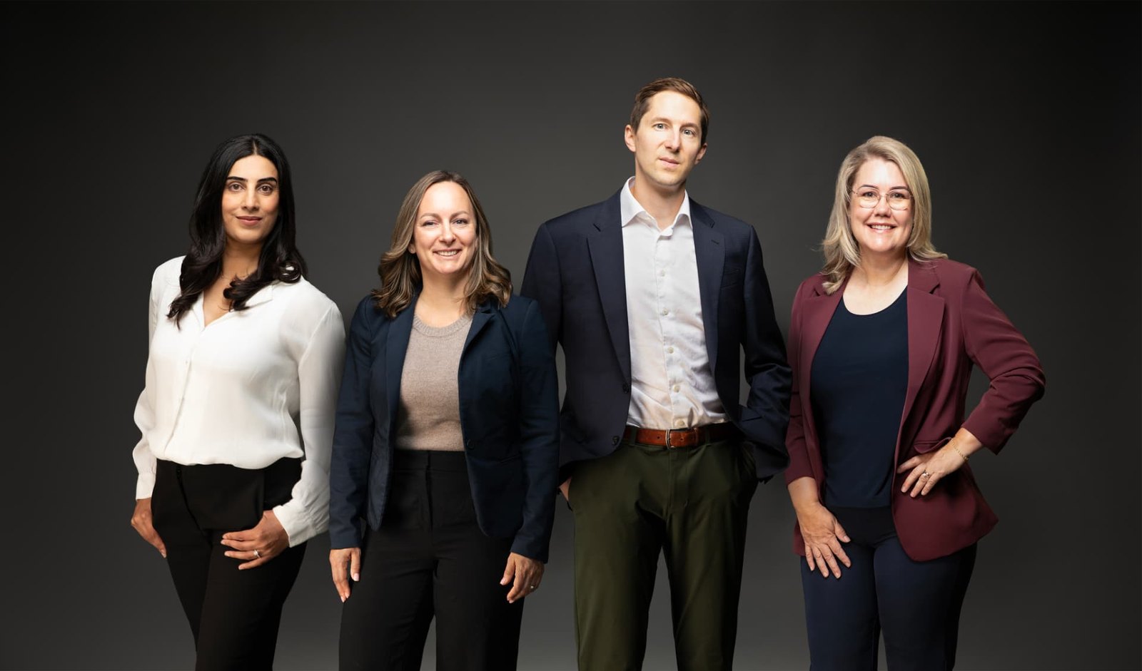Group portrait of four business partners standing together in a studio